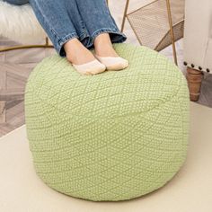 a woman sitting on top of a green bean bag chair with her feet propped up