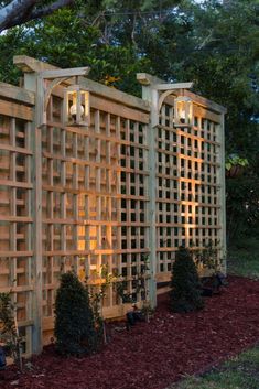 a wooden trellis is lit up in the evening