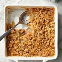 an apple crisp dessert in a white casserole dish with a spoon