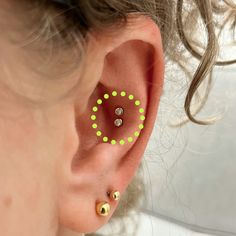 a woman with ear piercings that have green dots on the inside of her ear