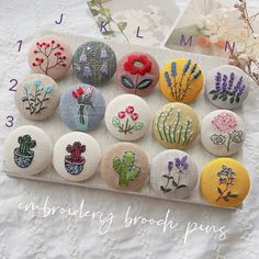 twelve embroidered brooches are arranged on a white surface with flowers and plants in them