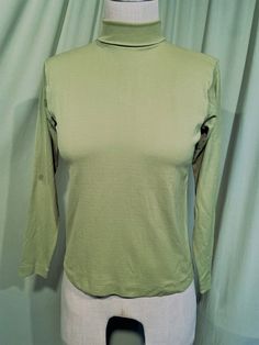 This is a sweet, vintage top from the 70s. No labels.  No size tag. The bust measures 34" without stretching, see measurements below.   Made of a bright olive green polyester, a bit brighter than the photos show.  The top has a folded turtleneck neckline that is stitched in the folded position & zips in the back with a nylon zipper. It has long sleeves. The top is in good condition!  Minimal wear.  No soil or stains.  Classic!  Measurements were taken with the garment lying flat. If you have never worn vintage before, please measure yourself!! Vintage sizes run smaller than today's sizes, know your measurements before buying! Bust measured from side seam to side seam at the underarm: 17" unstretched for a 34" or slightly smaller or larger bust Waist from side seam to side seam at the hemli Retro Stretch Long Sleeve Tops, Fitted Vintage Crew Neck Top, Fitted Cotton Turtleneck Top, Retro Green Tops For Fall, Green Stretch High Neck Top, Retro Solid Tops For Fall, Retro Stretch Top For Fall, Solid Retro Tops For Fall, Classic Green Stretch Top