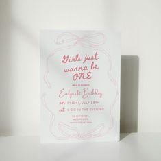 a white card with pink writing on it sitting on top of a table next to a vase