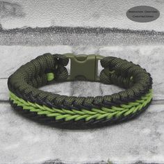 a green and black braided bracelet on concrete