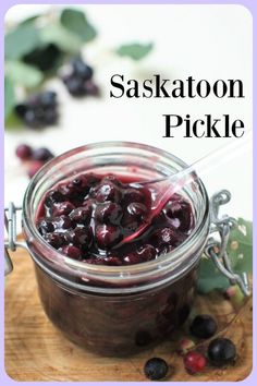 a glass jar filled with blueberry sauce on top of a wooden cutting board