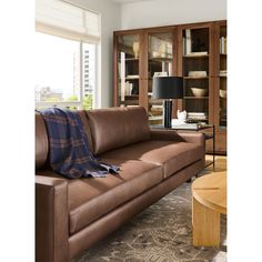 a living room filled with furniture and a lamp on top of a wooden table in front of a window