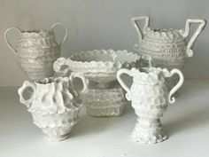 several white vases are sitting on a table