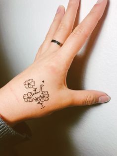 a woman's hand with a small flower tattoo on it