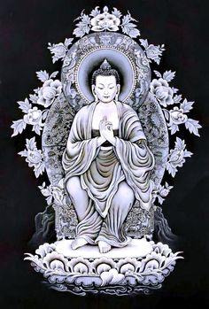 a buddha statue sitting on top of a white and black surface with flowers around it