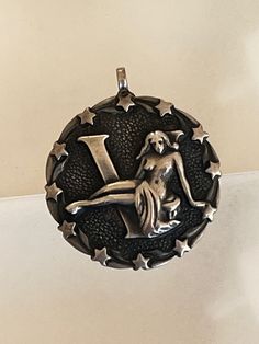 This listing features a vintage Sterling Silver VIRGO Pendant or Charm. The Pendant or Charm features a raised symbol of the maiden in the center of the charm, with the letter "V" in raised sterling silver, beneath the maiden. The center of the pendant or charm is beautifully appointed with swirls of silver and small stars in between each swirl. The background is pebbled giving the charm a multi dimensional look. The pendant or charm has a nice weight to it. There is a loop where you can insert a chain, leather cord or ribbon, or simply add it to a charm bracelet. Virgo is the Zodiac Horoscope sign for birthdays in August and September which includes those born between August 23 thru September 22. Virgo is the 6th of the 12 zodiac signs. Some of the traits of Virgos are being humble, indus Virgo Pendant, Small Stars, Zodiac Signs Virgo, Multi Dimensional, 12 Zodiac, Zodiac Pendant, Letter V, September 22, Zodiac Horoscope