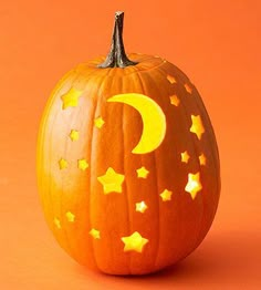 a carved pumpkin with the moon and stars painted on it's side, against an orange background