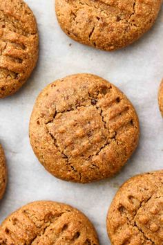 freshly baked peanut butter cookies lined up on a sheet of parchment paper with chocolate chips in the middle