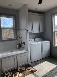 a washer and dryer sitting in a room next to a window with a rug on the floor