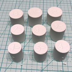 eight pill caps with numbers on them sitting on top of a piece of graph paper