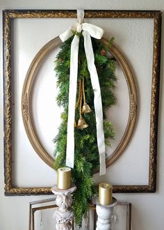 a christmas wreath is hung on the wall with two candles and a white ribbon around it