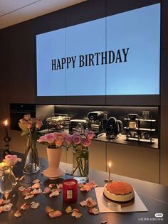 there is a birthday cake on the table with flowers and candles in front of it