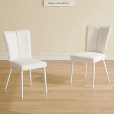 two white chairs sitting next to each other on top of a hard wood floored floor