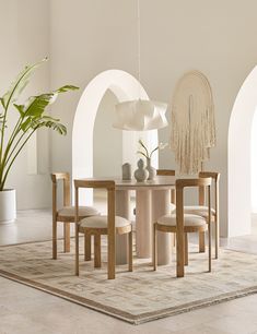 a dining table with chairs and a potted plant in the corner next to it