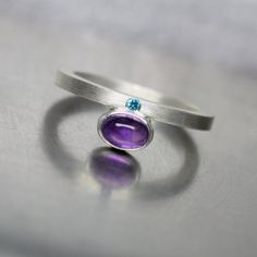 Such a modern and minimalistic design. Purpurblau consists of crisp lines and cool colors. A gorgeous 6x4mm oval amethyst is bezel set next to a 1.5mm paraiba blue topaz. Not much else matters but the simplicity of this solitaire ring.I fabricated this design from sterling silver in my studio.Ring Width: 2mmRing Thickness: 2mm*Made to order in your size (please allow 3-5 days)nangijalajewelry.etsy.com**Due to the handmade nature of this design you will receive a ring that is a very close copy bu Modern Oval Amethyst Ring With Polished Finish, Modern Amethyst Ring With Bezel Setting, Modern Amethyst Ring As Gift, Modern Topaz Promise Ring, Modern Oval Purple Jewelry, Modern Purple Oval Jewelry, Modern Topaz Ring With Accent Stones, Modern Sterling Silver Amethyst Ring, Modern Silver Oval Topaz Ring