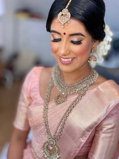 a woman in a pink sari with jewelry on her neck and shoulder, smiling at the camera