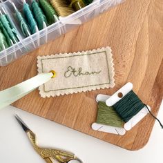 a pair of scissors and some thread sitting on a cutting board next to sewing supplies