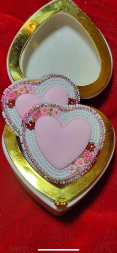 two heart shaped cookies in a gold and white box