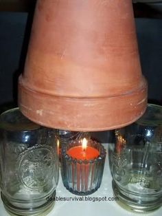 a candle is lit in front of two glass cups and a clay hat on top