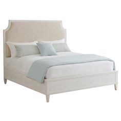 a white bed with blue pillows and sheets on it's headboard, in front of a white background