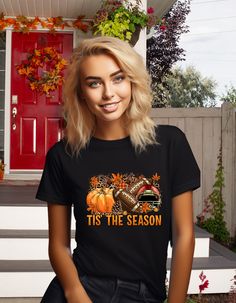 Get ready for football, pumpkin season, and the fall weather with the Tis The Season Autumn Graphic T-Shirt! This cute and bold t-shirt is perfect for football watch parties and pairs perfectly with your favorite jeans and sneakers. Made with Gilden softstyle fabric, it's fade resistant and preshrunk. Size up for an oversized look. Black T-shirt For Fall Game Day, Black T-shirt For Game Day In Fall, Fall Season Black Top For Sports Fans, Fall Fan Apparel T-shirt With Graphic Print, Fall Crew Neck T-shirt For Fan Gear, Fall Fan Gear T-shirt With Crew Neck, Fan Apparel Graphic T-shirt For Fall, Fan Apparel Graphic Print T-shirt For Fall, Fall Graphic Tee For Fan Merchandise