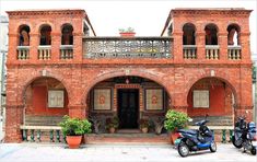 two mopeds are parked in front of an old red brick building with ornate balconies