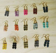 several pairs of earrings are displayed on a wooden surface, with different colors and shapes