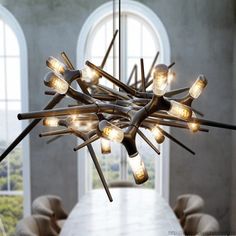 a chandelier made out of wooden sticks with lights hanging from the ceiling above it