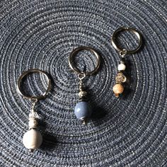 three pairs of earrings sitting on top of a gray cloth covered table next to each other