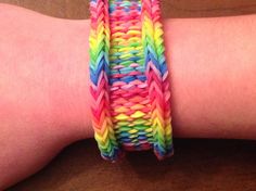 a woman's arm with two different colored bracelets on it, one is made out of multicolored paper and the other has a rubber band