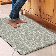 a woman standing on a kitchen floor with her feet up in the middle of an area rug