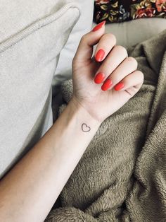 a woman's arm with a small heart tattoo on it