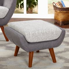 a grey ottoman sitting on top of a wooden floor next to a basket filled with books