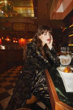 a woman sitting at a bar with her hand on her chin and looking off to the side