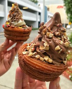 two people holding up some very tasty looking pastries with chocolate frosting and nuts