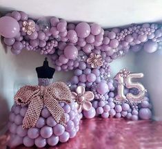 a number 15 made out of balloons with a dress on the top and flowers in the bottom