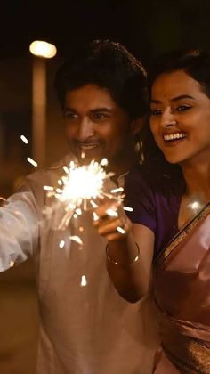 a man and woman holding sparklers in their hands