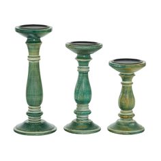 three green candlesticks sitting next to each other