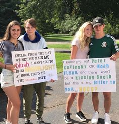 three young people holding up signs in the middle of a road with trees and grass behind them