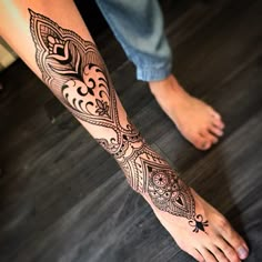 a person with a tattoo on their foot is standing in front of a wooden floor