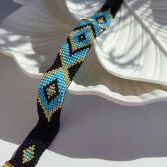 a blue and black beaded bracelet sitting on top of a white plate