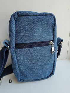 This bag is perfect for those who don't want to carry around a big bag, but still have a few things to carry. It's made with upcycled denim and has a pretty cotton lining.   The zippered main compartment is about 5 inches wide, 8 inches tall, and 2 1/2 inches deep.  The lightly padded inside phone pocket is about 4 1/2 inches wide and 5 1/2 inches deep and is perfect to keep your phone easy to grab and scratch-free. The outer pocket is about 4 1/2 inches wide and 5 inches deep and has a zipper to keep your cash and ID card safe and secure.  The outside of the bag also has a clip to easily hook your keys onto. The strap is made with sturdy cotton strapping and metal hardware that matches the zippers. The strap measures 30 inches to 54 inches long so it can be worn as a shoulder bag or a cro Denim Blue Shoulder Bag With Zipper For School, Casual Cotton Shoulder Bag With Mobile Phone Pocket, Denim Blue Bags With Cell Phone Pocket For Everyday, Denim Blue Bag With Cell Phone Pocket For Everyday, Everyday Cotton Mobile Phone Bag, Denim Blue Shoulder Bag With Zipper For Everyday Use, Everyday Denim Blue Bag With Cell Phone Pocket, Everyday Denim Shoulder Bag With Cell Phone Pocket, Casual Denim Shoulder Bag With Cell Phone Pocket