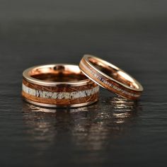 two gold wedding bands with white and brown wood inlays, set on top of each other