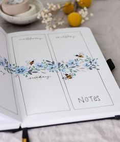 an open notebook with blue flowers on it and writing notes in the pages next to some lemons