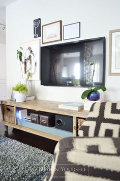 a flat screen tv mounted to the side of a wooden entertainment center in a living room