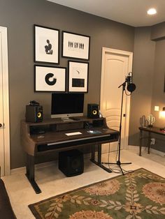 a computer desk sitting in the middle of a living room with pictures on the wall